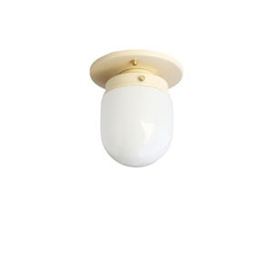 May include: Cream-colored ceiling light fixture with a rounded, opaque white glass shade. The fixture has a circular base and a cylindrical body, with brass-colored accents. The design is simple and modern.