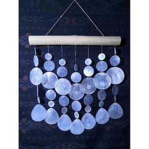 May include: A white shell wind chime with a bamboo top. The shells are arranged in a cascading pattern, with the largest shells at the top and the smallest shells at the bottom.