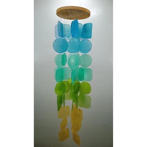 Può includere: Un carillon di vetro con una cima in legno. I pezzi di vetro sono in tonalità di blu, verde e giallo.