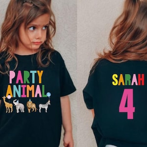 May include: Black t-shirt with the words "PARTY ANIMAL" in colorful letters and animal graphics. The back of the shirt has the name "SARAH" and the number "4" in bright colors. A fun birthday shirt.