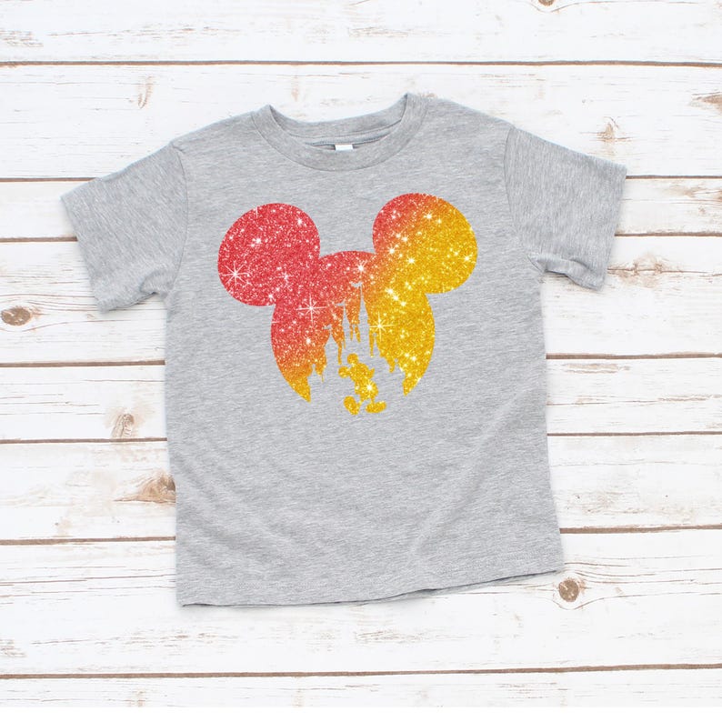 Puede incluir: Una camiseta gris con una silueta brillante de Mickey Mouse en rojo y amarillo. El dise&ntilde;o incluye un castillo y Mickey Mouse. La camiseta est&aacute; hecha de un material suave y es adecuada para ni&ntilde;os.