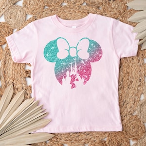 Puede incluir: Camiseta rosa claro con un dise&ntilde;o brillante de Minnie Mouse. El dise&ntilde;o presenta un lazo y orejas en turquesa y rosa, con una silueta de castillo en el centro. Ropa para ni&ntilde;os.