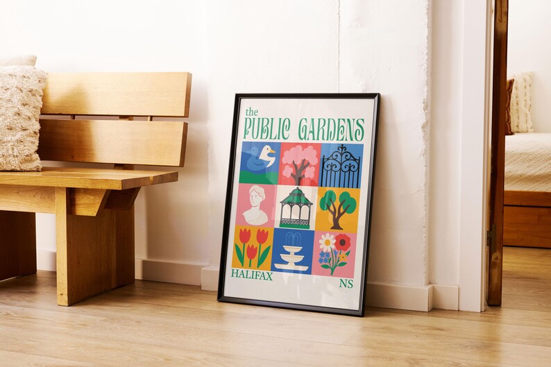 Op de afbeelding: Een ingelijste poster getiteld "The Public Gardens" met kleurrijke illustraties van een eend, boom, poort, buste, tuinhuisje, boom, tulpen, fontein, bloem en de tekst "Halifax NS". De poster leunt tegen een witte muur.