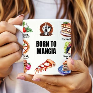 Puede incluir: Taza de cerámica blanca con un diseño en blanco y negro que presenta el texto "Born to Mangia" e ilustraciones de comida italiana, incluyendo pizza, café y tiramisú.