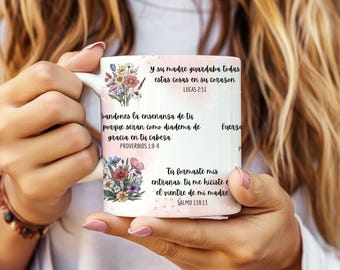 May include: White ceramic mug with a floral design and inspirational quotes in Spanish. The quotes are from the Bible, including Lucas 2:51, Proverbs 1:8-9, and Salmo 139:13.