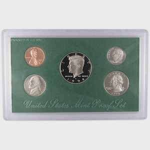 May include: A 1998 United States Mint Proof Set, packaged in a clear plastic case. The set includes five coins: a penny, a half dollar, and three other coins, all displayed on a green background. The text "United States Mint Proof Set" is visible.