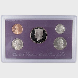 May include: A 1992 United States Mint Proof Set. The set includes a penny, nickel, half dollar, dime, and quarter, all in a protective case. The coins are displayed on a purple background, with the words "United States Mint Proof Set" at the bottom.