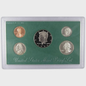May include: A 1995 United States Mint Proof Set in a clear plastic case. The set includes a copper penny, a silver half-dollar, a nickel, a dime, and a quarter, all displayed on a green background. The text "United States Mint Proof Set" is visible.