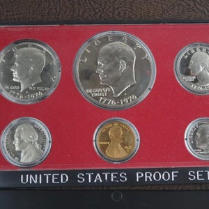 May include: A United States Proof Set from 1976, featuring various coins with historical figures and the text "In God We Trust" and "Liberty". The coins are displayed on a red background within a black case, with the words "United States Proof Set" at the bottom.