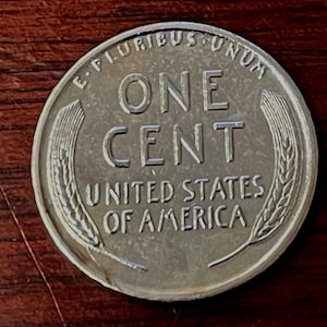 May include: A silver US one-cent coin with the words "E Pluribus Unum", "One Cent", "United States of America", and a wheat stalk design.