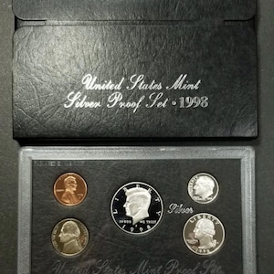 May include: A 1998 United States Mint Silver Proof Set in a black case. The set includes a penny, nickel, half dollar, and two silver coins. The case is embossed with "United States Mint Silver Proof Set 1998".