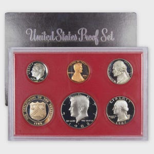 May include: A United States Proof Set in a red case. The set includes six coins with portraits of historical figures. The case is labeled "United States Proof Set". The coins are in excellent condition, with a shiny, reflective surface.