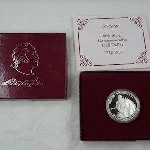 May include: A commemorative half-dollar coin, 90% silver, in a burgundy box. The coin features George Washington and the text "50th Anniversary of Boxing". The box lid has a silver profile of Washington.