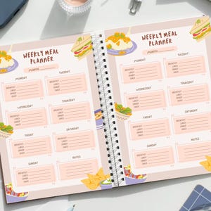 May include: A weekly meal planner with a pink background and illustrations of food. The planner has spaces to write in meals for each day of the week, including breakfast, lunch, dinner, and snacks.