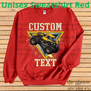 K&ouml;nnte beinhalten: Ein rotes Unisex-Sweatshirt mit einem gelb-schwarzen Monstertruck-Design in einem gelben Dreieck. Die W&ouml;rter "CUSTOM" und "TEXT" sind deutlich sichtbar. Oben auf dem Sweatshirt steht "Unisex Sweatshirt Red".