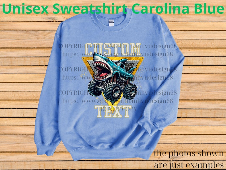 May include: Carolina blue unisex sweatshirt with a graphic of a shark-themed monster truck. The design includes the word "CUSTOM" above the truck and "TEXT" below. The sweatshirt is a solid color with a crew neck.