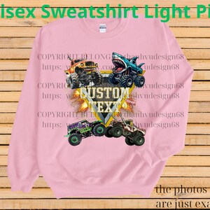 May include: Light pink unisex sweatshirt featuring a graphic of monster trucks in various colors. The design includes the text "CUSTOM TEXT" and the words "Unisex Sweatshirt Light Pink". The photos shown are just examples.