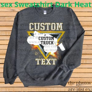 May include: Dark heather grey unisex sweatshirt with a custom design. The design features the word "CUSTOM" above a yellow triangle with the words "CUSTOM TRUCK TEXT" inside. The sweatshirt has long sleeves and a crew neck.