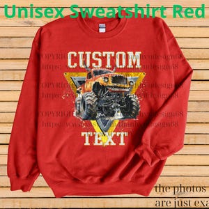 May include: Red unisex sweatshirt with a graphic of a monster truck inside a yellow triangle. The words "CUSTOM" and "TEXT" are displayed. The sweatshirt also has the text "Unisex Sweatshirt Red".