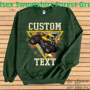 K&ouml;nnte beinhalten: Forstgr&uuml;nes Unisex-Sweatshirt mit einem gelben Monstertruck-Motiv in einem gelben Dreieck. Die W&ouml;rter "CUSTOM" und "TEXT" stehen &uuml;ber und unter dem Truck. Das Sweatshirt ist aus weichem Material.