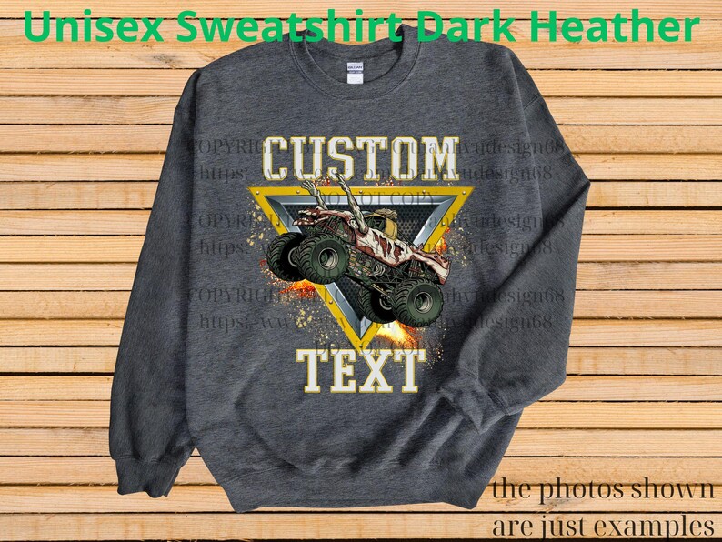 May include: Dark heather grey unisex sweatshirt with a custom design. The design features a monster truck graphic inside a yellow triangle, with the words "CUSTOM" and "TEXT". The sweatshirt is a comfortable, casual style.