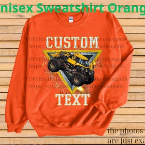 K&ouml;nnte beinhalten: Orangefarbenes Unisex-Sweatshirt mit einer Grafik eines gelben Monstertrucks in einem gelben Dreieck. Das Wort "CUSTOM" steht &uuml;ber dem Truck, und "TEXT" steht darunter. Der Text "Unisex Sweatshirt Orange" steht oben.