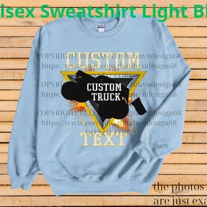 May include: Pale blue unisex sweatshirt featuring a custom truck graphic within a yellow triangle. The design includes the words "CUSTOM TRUCK" and "TEXT". The image also includes the text "COPYRIGHT BELONG TO" and a website address.