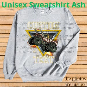 May include: A light grey unisex sweatshirt featuring a monster truck graphic within a yellow triangle. The text "CUSTOM TEXT" is below the triangle. The words "Unisex Sweatshirt Ash" are at the top.