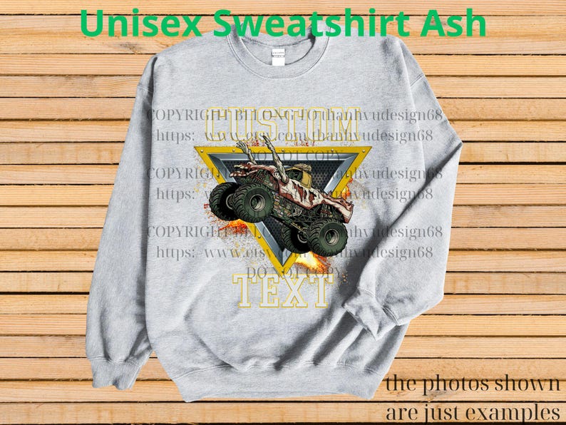 May include: A light grey unisex sweatshirt featuring a monster truck graphic within a yellow triangle. The text "CUSTOM TEXT" is below the triangle. The words "Unisex Sweatshirt Ash" are at the top.