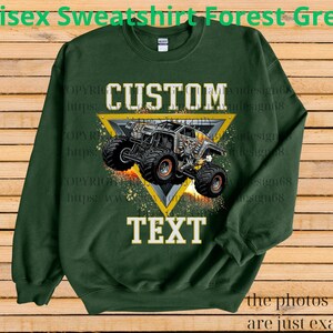 May include: Forest green unisex sweatshirt with a custom monster truck design. The design features a monster truck inside a yellow triangle with the words "CUSTOM" and "TEXT" in white. The sweatshirt is a crew neck.