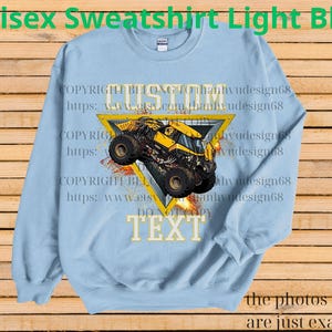 K&ouml;nnte beinhalten: Hellblaues Unisex-Sweatshirt mit individuellem Design. Das Design zeigt einen gelb-schwarzen Monstertruck in einem gelben Dreieck, mit dem Wort "CUSTOM" dar&uuml;ber und "TEXT" darunter. Der Text "Unisex Sweatshirt Light Blue" steht oben.
