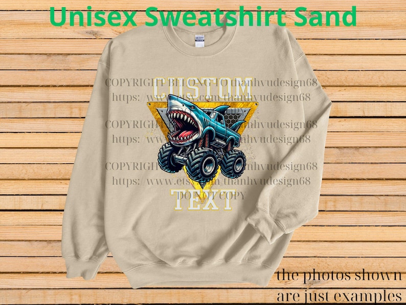 May include: Sand-colored unisex sweatshirt featuring a shark-themed monster truck design. The graphic includes a blue truck with a shark head, large tires, and the text "DO NOT COPY". The sweatshirt also has the text "Unisex Sweatshirt Sand".