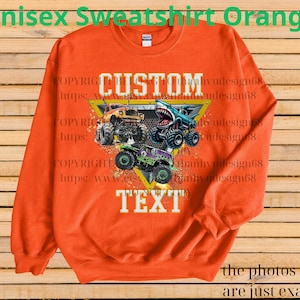 May include: Orange unisex sweatshirt featuring a graphic of three monster trucks with the text "CUSTOM TEXT". The design includes a yellow triangle and the text "the photos shown are just examples".