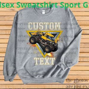 K&ouml;nnte beinhalten: Graues Unisex-Sweatshirt mit einem gelb-schwarzen Monster-Truck-Motiv in einem gelben Dreieck. Die W&ouml;rter "CUSTOM" und "TEXT" sind abgebildet. Der Text oben lautet "Unisex Sweatshirt Sport Grey".
