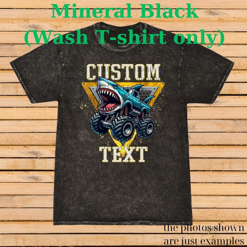 May include: Black mineral wash t-shirt with a graphic of a shark-themed monster truck. The design includes the words "CUSTOM" and "TEXT" in a yellow triangle. The shirt is a dark gray color.