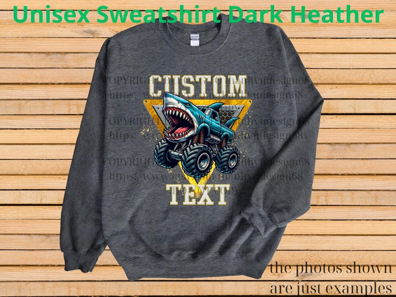May include: Dark heather gray unisex sweatshirt featuring a cartoon monster truck with a shark head. The design includes the words "CUSTOM" and "TEXT" in a yellow triangle. The sweatshirt is a comfortable, casual style.