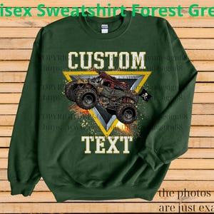 May include: Forest green unisex sweatshirt with a custom design featuring a monster truck graphic. The design includes the words "CUSTOM" and "TEXT" in white, set against a yellow triangle.