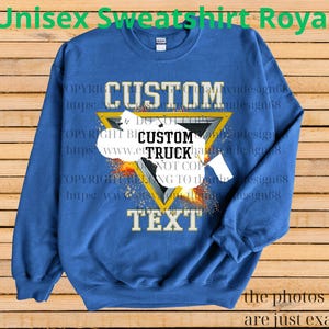 May include: Royal blue unisex sweatshirt with a custom design. The design features a white truck graphic inside a yellow triangle, with the words "CUSTOM" and "TEXT" above and below. The sweatshirt has the text "Unisex Sweatshirt Royal" at the top.