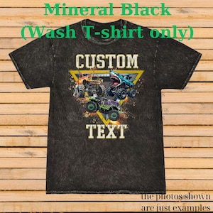 May include: A black mineral wash t-shirt featuring a graphic of three monster trucks inside a yellow triangle. The word "CUSTOM" is above the trucks, and "TEXT" is below. The shirt has the text "Mineral Black (Wash T-shirt only)" at the top.