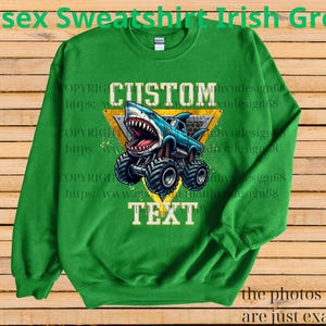 May include: Irish green unisex sweatshirt with a graphic of a shark-themed monster truck. The design includes the words "CUSTOM" and "TEXT" within a yellow triangle. The sweatshirt is made of a soft material.