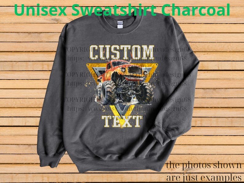 May include: Charcoal gray unisex sweatshirt featuring a monster truck design. The design includes a yellow triangle with the words "CUSTOM" and "TEXT" and a monster truck illustration. The text "Unisex Sweatshirt Charcoal" is at the top.