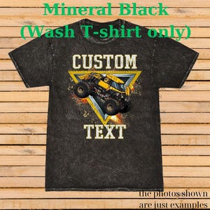 K&ouml;nnte beinhalten: Mineral-schwarzes Wasch-T-Shirt mit individuellem Design. Das Design zeigt einen gelb-schwarzen Monstertruck in einem gelben Dreieck, mit dem Wort "CUSTOM" dar&uuml;ber und "TEXT" darunter.