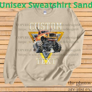 May include: Sand-colored unisex sweatshirt featuring a monster truck graphic within a yellow triangle. The text "CUSTOM" and "TEXT" are visible, along with the phrase "DO NOT COPY." The sweatshirt also has the text "Unisex Sweatshirt Sand."