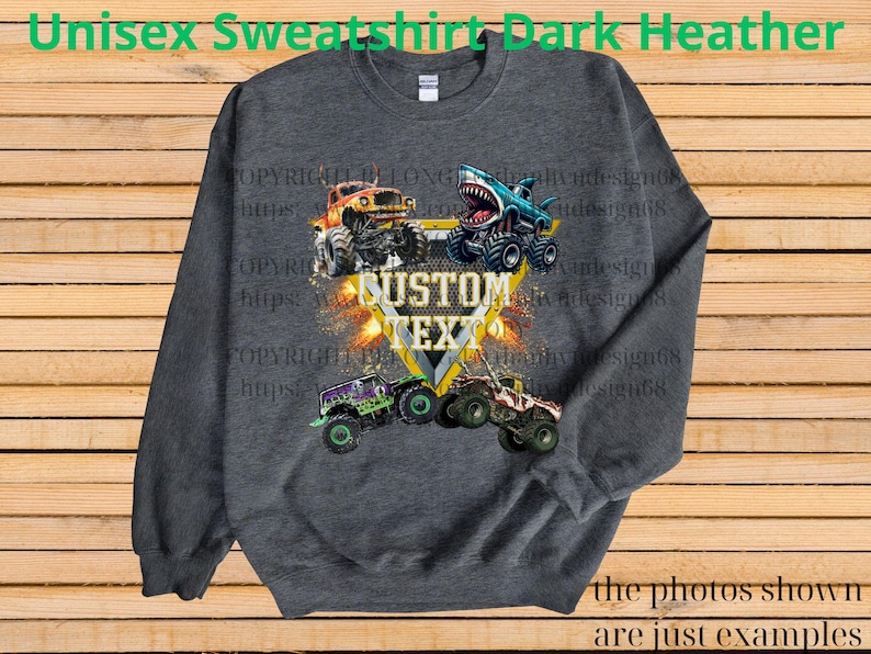 May include: Dark heather gray unisex sweatshirt featuring a graphic of monster trucks with the text "CUSTOM TEXT". The design includes a shark-themed truck and other colorful trucks. The text "Unisex Sweatshirt Dark Heather" is at the top.