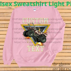 May include: Pale pink unisex sweatshirt featuring a monster truck design. The graphic shows a monster truck with flames, set within a yellow triangle. The text "CUSTOM TEXT" is below the truck. The sweatshirt has the text "Unisex Sweatshirt Light Pink" at the top.