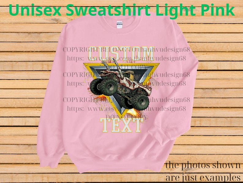 May include: Pale pink unisex sweatshirt featuring a monster truck design. The graphic shows a monster truck with flames, set within a yellow triangle. The text "CUSTOM TEXT" is below the truck. The sweatshirt has the text "Unisex Sweatshirt Light Pink" at the top.