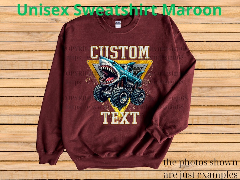 May include: Maroon unisex sweatshirt featuring a custom design. The design includes a blue monster truck with a shark head, set against a yellow triangle. The word "CUSTOM" is above the graphic, and "TEXT" is below.