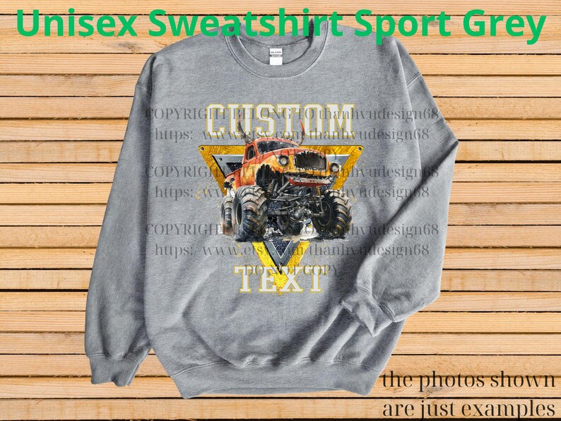 May include: A gray unisex sweatshirt with a graphic of a monster truck inside a yellow triangle. The text "CUSTOM TEXT" is displayed on the design. The words "Unisex Sweatshirt Sport Grey" are at the top.