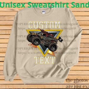 May include: Sand-colored unisex sweatshirt featuring a graphic of a monster truck with a skull and crossbones flag. The design is set within a yellow triangle with the words "CUSTOM TEXT" and "DO NOT COPY". The sweatshirt has the text "Unisex Sweatshirt Sand" at the top.