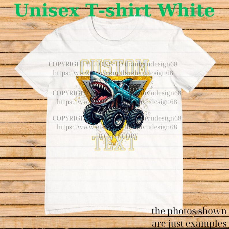 May include: White unisex t-shirt featuring a blue monster truck with a shark head design. The shark has an open mouth with visible teeth. The shirt has the text "CUSTOM TEXT" in a yellow triangle.